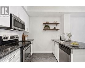A kitchen with white cabinets and black countertops.