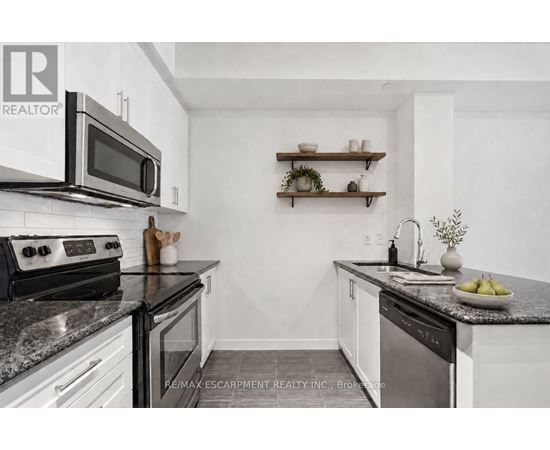 A kitchen with white cabinets and black countertops.
