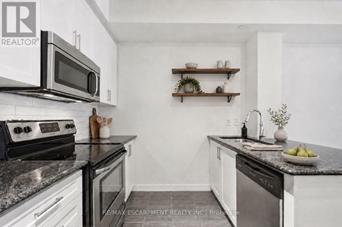 A kitchen with white cabinets and black countertops.