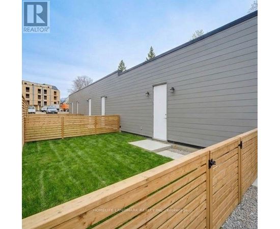 A grey building with a white door and a wooden fence in front.