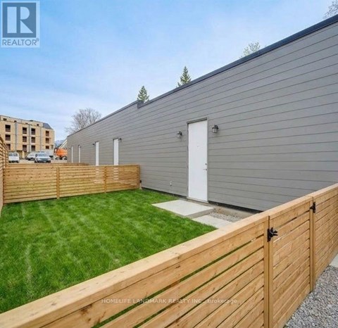 A grey building with a white door and a wooden fence in front.