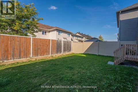 A backyard with a wooden fence and a green lawn.