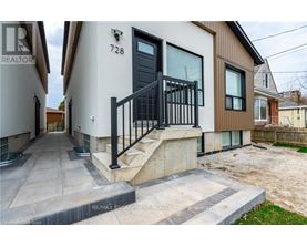A modern house with a black door and a black railing on the stairs.
