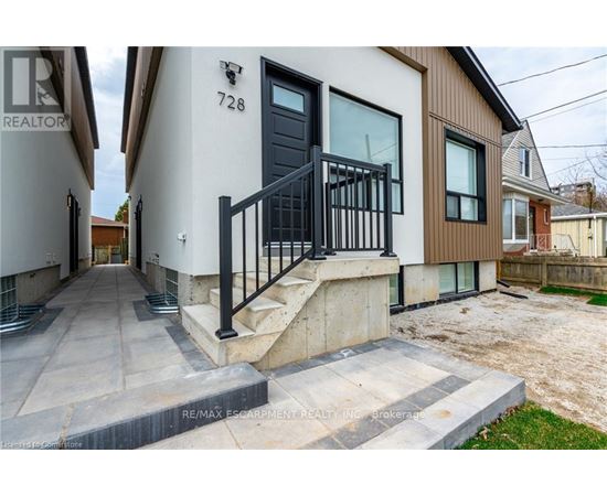 A modern house with a black door and a black railing on the stairs.