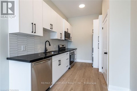 A kitchen with white cabinets and a black countertop.