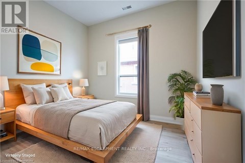 A bedroom with a bed, nightstand, and a painting on the wall.