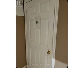 A white door with a gold doorknob and a sign that says "B".