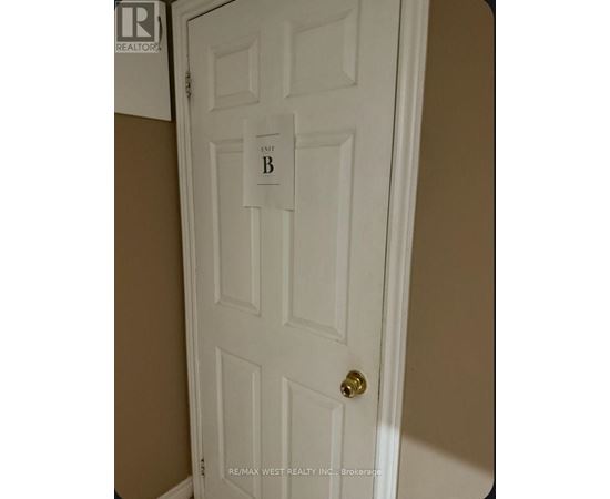 A white door with a gold doorknob and a sign that says "B".