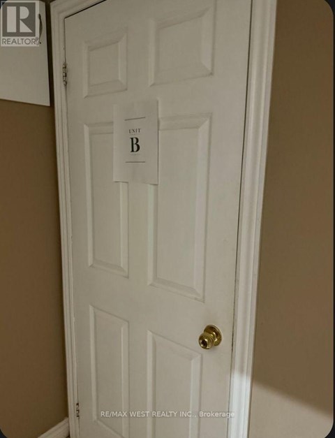 A white door with a gold doorknob and a sign that says "B".
