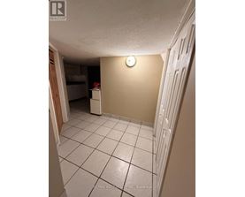 A white tiled hallway with a light switch on the wall.