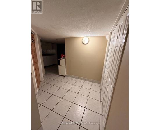 A white tiled hallway with a light switch on the wall.