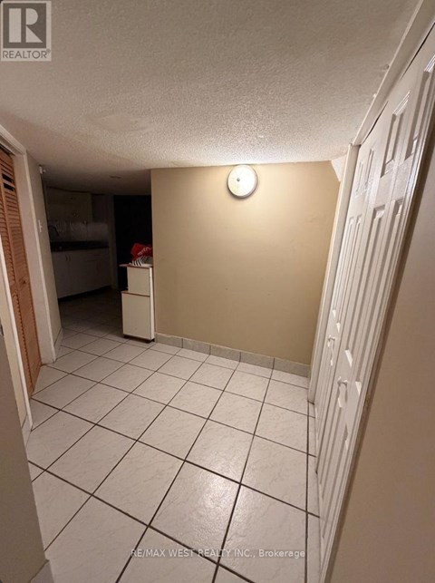 A white tiled hallway with a light switch on the wall.