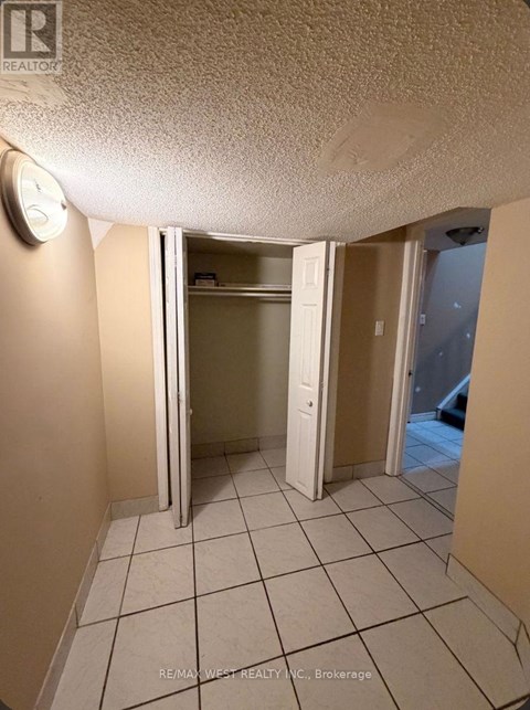 A room with a clock on the wall and a door open to another room.