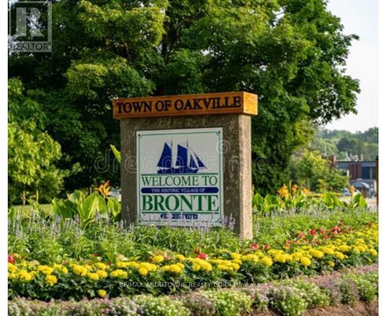 A sign that says "Town of Oakville Welcome to Bronte" is in front of some flowers.