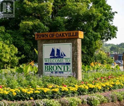 A sign that says "Town of Oakville Welcome to Bronte" is in front of some flowers.