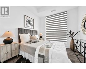A bedroom with a bed, nightstand, and a framed picture on the wall.