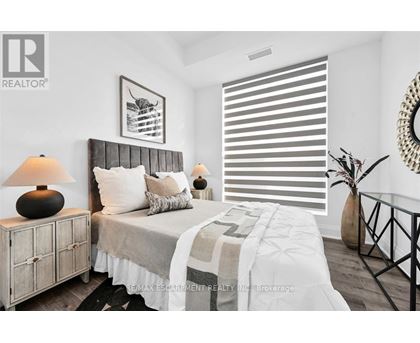 A bedroom with a bed, nightstand, and a framed picture on the wall.