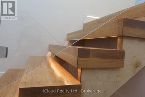 A wooden staircase with glass balustrade.