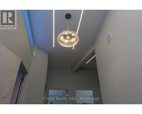A modern interior space with a hanging light fixture and a wall-mounted sign for iCloud Realty Ltd., Brokerage.