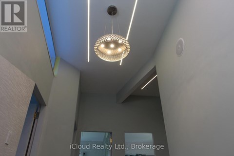 A modern interior space with a hanging light fixture and a wall-mounted sign for iCloud Realty Ltd., Brokerage.