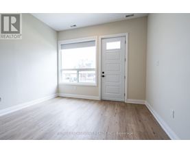 A room with a white door and a window with a view of a building.