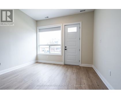 A room with a white door and a window with a view of a building.