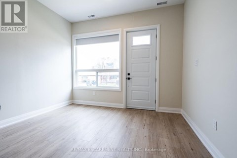 A room with a white door and a window with a view of a building.