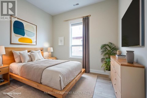 A bedroom with a bed, nightstand, and a painting on the wall.