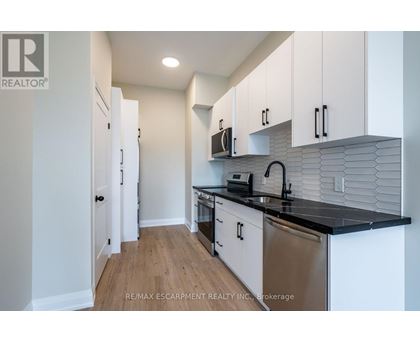 A kitchen with white cabinets and a black counter top.