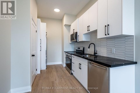 A kitchen with white cabinets and a black counter top.