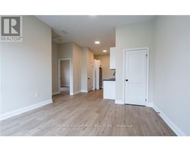 A spacious room with wooden flooring and white walls.