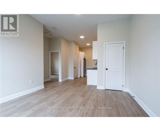 A spacious room with wooden flooring and white walls.