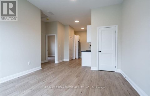 A spacious room with wooden flooring and white walls.