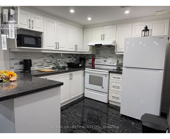A kitchen with white cabinets and black countertops.
