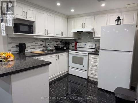 A kitchen with white cabinets and black countertops.