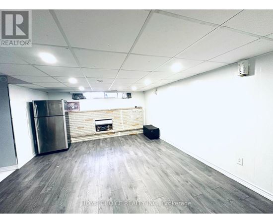 A spacious room with a wooden floor, a stainless steel refrigerator, and a fireplace.