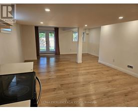 A spacious room with wooden flooring and a black stove top oven.