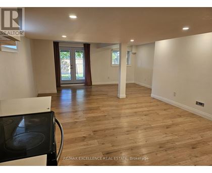 A spacious room with wooden flooring and a black stove top oven.
