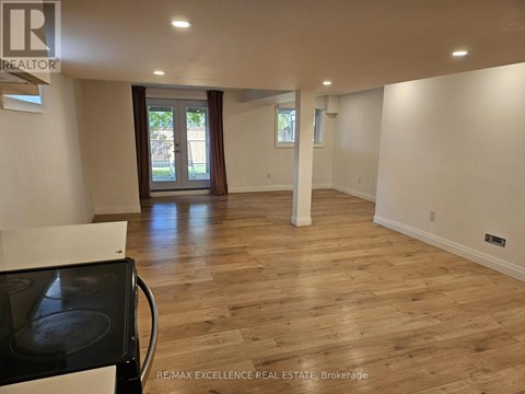 A spacious room with wooden flooring and a black stove top oven.