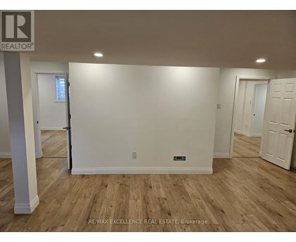 A room with wooden flooring and white walls, with a door on the left and a door on the right.