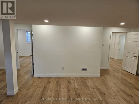 A room with wooden flooring and white walls, with a door on the left and a door on the right.