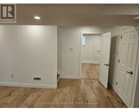 A room with wooden flooring and white walls, with a door on the right.