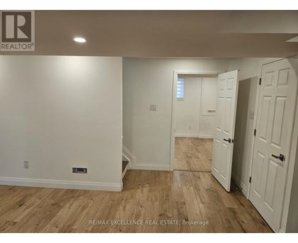 A room with wooden flooring and white walls, with a door on the right.