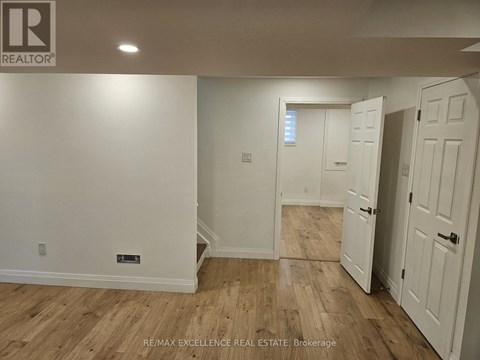A room with wooden flooring and white walls, with a door on the right.