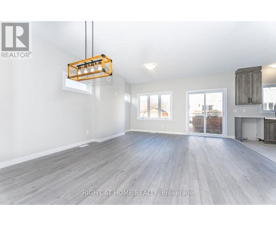 A spacious room with wooden flooring and a hanging light fixture.