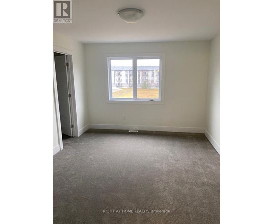 A room with a carpeted floor and a window showing a view of a building outside.