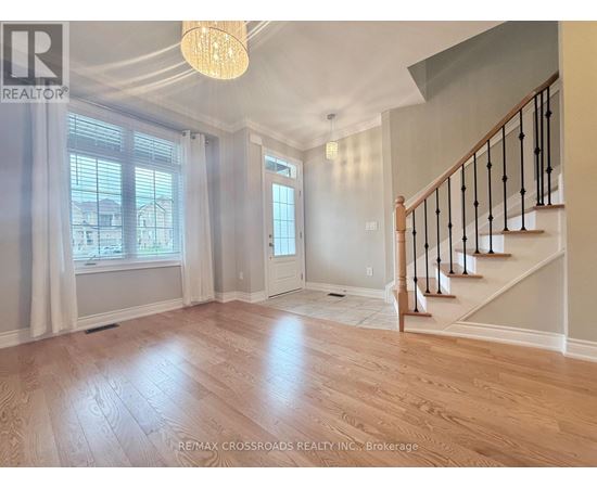 A well-lit, spacious room with wooden flooring and a staircase with black railings.