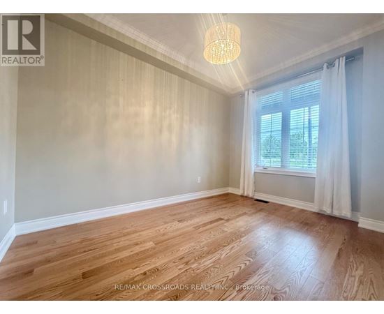 A room with wooden flooring and a window with white curtains.