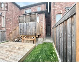 A wooden deck leads to a brick building with a wooden fence on the right.