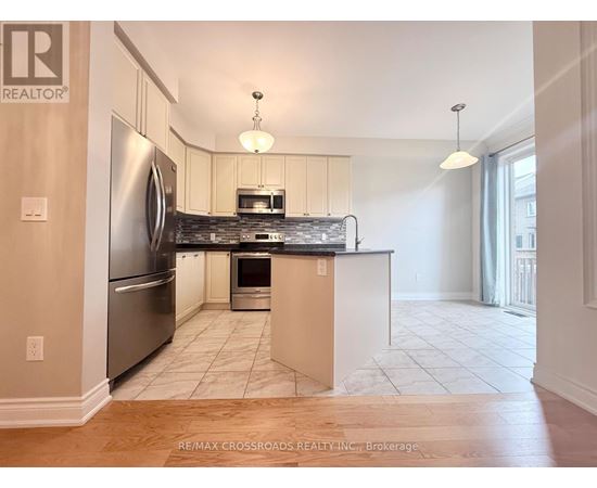A kitchen with a refrigerator, microwave, oven and sink.
